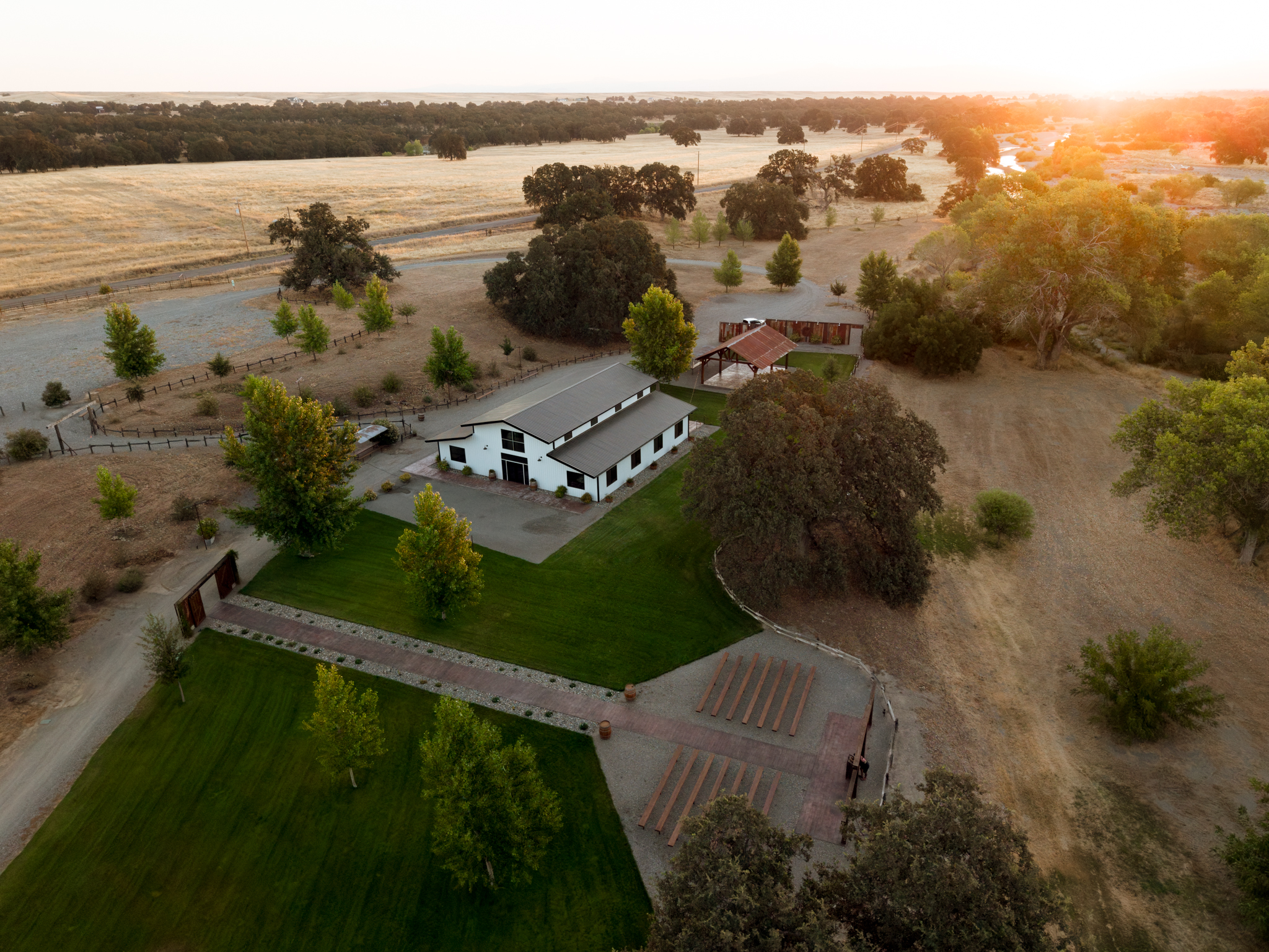 Aerial view of the whole ranch at sunset, barn, pavilion, ceremony lawn and oaks